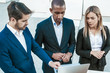 © Mangostar - Focused business group excited with presentation on laptop screen. Two serious men and woman standing outdoors and looking at monitor. Watching content concept