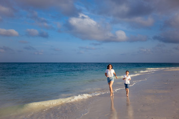 Happy family on vacation: mother and son are walking along the ocean. Seychelles