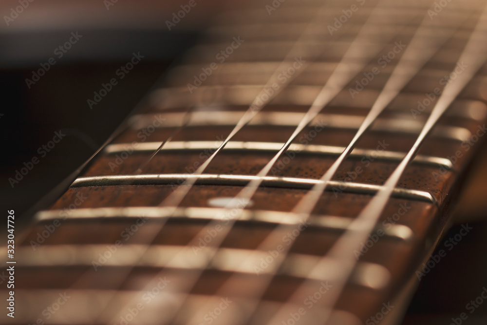 Macro photo of a guitar strings in perspective. Parts of the guitar for good sound and melody. Beautiful musical background in red and brown tones. - obrazy, fototapety, plakaty 