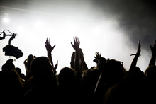 Stage Lights And Crowd Of Audience With Hands Raised At A Music Festival. Fans Enjoying The Party Vibes.