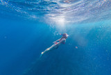 Fototapeta Łazienka - Girl with a mask and a snorkel dives into the sea with corals and fish