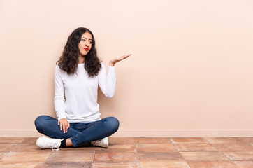 Wall Mural - Young woman sitting on the floor holding copyspace with doubts