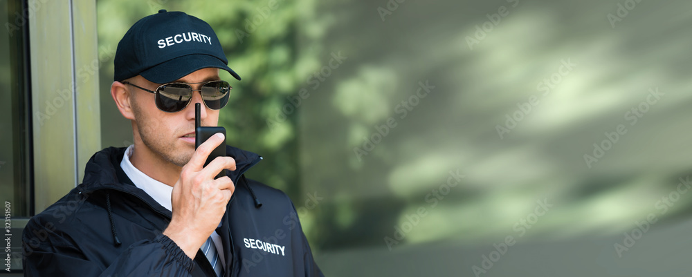 Young Security Guard Talking On Walkie-talkie - obrazy, fototapety, plakaty 