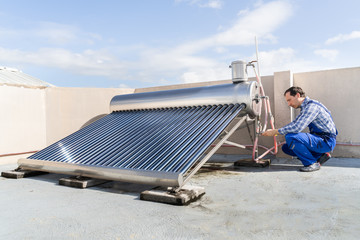 Male Plumber Repairing Solar Energy Boiler