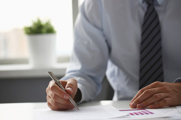 Hand of businessman in suit filling and signing with silver pen partnership agreement form clipped to pad closeup. Management training course, some important document, team leader ambition concept