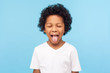 © khosrork - Portrait of funny naughty little boy with curly hair in T-shirt sticking out tongue and keeping eyes closed, disobedient child foolishing with cute derisive expression. studio shot blue background
