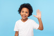 © khosrork - Portrait of amazing friendly little boy grinning happily and waving hi, gesturing hello with raised arm, welcoming greeting, expressing joy from meeting. indoor studio shot isolated on blue background