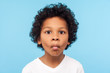 © khosrork - Closeup portrait of funny goofy little boy with curly hair making fish face with pout lips and big eyes, child looking confused with comical expression. indoor studio shot isolated on blue background