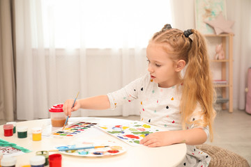 Sticker - Cute little child painting at table in room