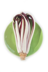 Radicchio tardivo, italian red chicory on a green plate on wooden background. Italian red salad on table