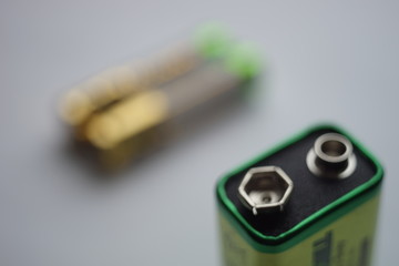 green alkaline battery close-up, two finger batteries on a blurred background.