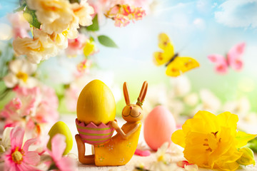 Wall Mural - Easter decoration with bunny, Easter eggs and beautiful spring flowers on a blurred light background. Easter concept with copy space
