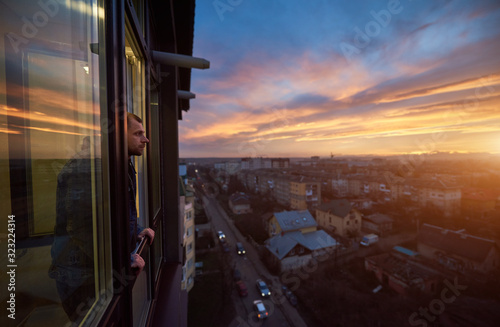 Fotomural Adult man stands on the balcony and looks into the distance enjoying the sunset