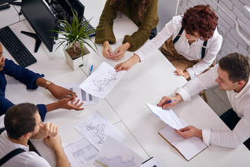 Top view on business team during meeting conference working with documents about marketing plan, papers on table, working process