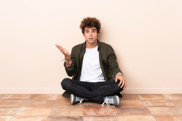 Wall Mural - Young caucasian man sitting on the floor making doubts gesture