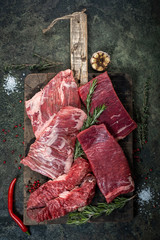 Wall Mural - Set of fresh raw alternative beef steaks on a wooden Board: Denver, Skirt, Flank, Machete and rosemary, top view