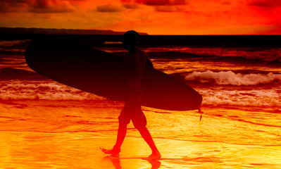 Silhouette Of surfer young man carrying their surfboard on sunset beach, vintage filter effect image