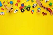 Set Of Colorful Wooden Toys For Kids, Cars, Trains, Building Blocks On Yellow Background, Copy Space.