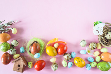 Wall Mural - Festive easter holiday background. Various easter eggs, bird house, nest on pink background. Space for text, flat lay