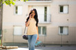 © mimagephotos - beautiful young hispanic woman walking and talking with mobile phone in city