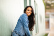 © mimagephotos - smiling young brunette woman leaning against wall