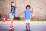 Two happy kids boy and girl roller skate in the park. Children and activity concept