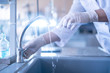 © Mihail - person hands in gloves cleaning and washing glass flasks with water in laboratory