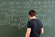 © Mihail - male person writing text with piece of chalk on blackboard, doing maths and physics equations