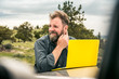 © MACO - Bearded man with laptop on truck observing rural prairie setting. Cody, Wyoming, USA