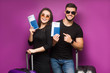 © Тарас Нагирняк - Portrait of successful lucky couple getting visa abroad holding raised fist showing passport with flying tickets shouting with wide open mouth isolated on violet background.