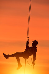Wall Mural - Construction worker wearing safety work at high uniform on scaffolding at construction site on during sunset,Working at height equipment.