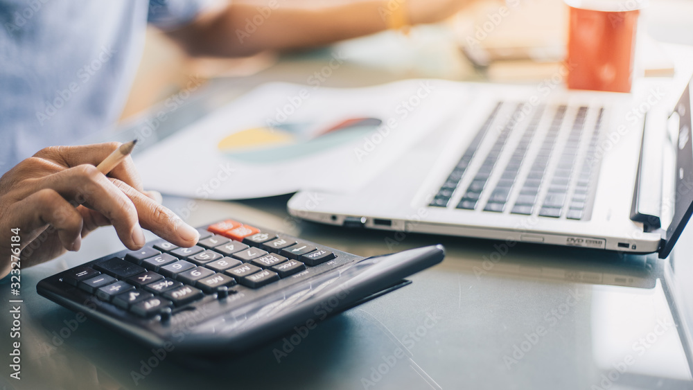 Businessman using calculator for analysis maketing plan, Accountant calculate financial report, computer with graph chart. Business, Finance and Accounting concepts  - obrazy, fototapety, plakaty 