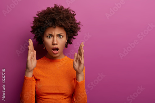 Fotomural Displeased emotional woman with Afro hairstyle shapes someting big, impressed ba