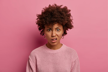 portrait of angry displeased woman smirks face, expresses scorn and disdain, raises eyebrows, stares