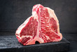 Rohes dry aged Wagyu Porterhouse Rinder Steak mit großen Filet Stück als closeup auf einem schwarzen verbrannten Holz Board mit Textfreiraum