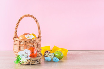 Wall Mural - Beautiful easter and spring holiday still life. Wicker basket with easter eggs, nest and bouquet of willow on light blue wooden background. Space for text