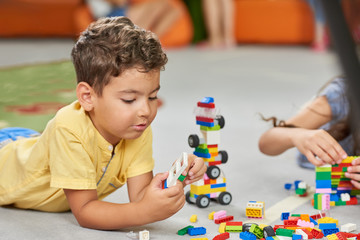 Wall Mural - Kids playing with toys on the floor. Happy children playing blocks at childrens center. Developing activities for kids.