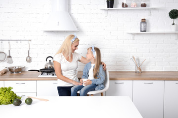 Mom with daughter in the kitchen. Family, cooking and people concept - happy mother with little daughter making cookies and having fun at home kitchen