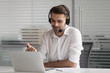 Smiling male worker in headset talking on video call