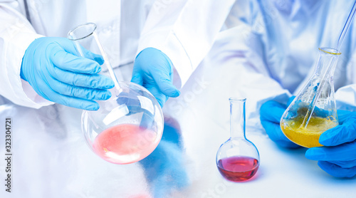 Fotomural The hands of the chemists in gloves holding the flasks