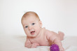 © ritiniya - Cute naked baby lies on his stomach and holds a massage ball. on white background. Children's massage. massage of the newborns. firming massage for babies. fine motor skills of hands.