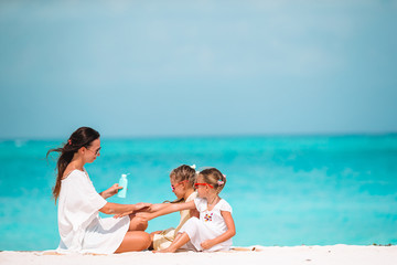 Wall Mural - Young mother applying sun cream to daughter nose on the beach. Sun protection