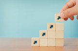 Business concept of ladder career path and growth success process. Hands of men arranging wood cube block stacking as step stair with arrow up.