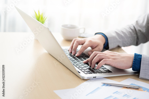 Fotomural Young businessman is typing the business performance results on laptop computer keyboard
