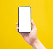 © Touchr - Male hand holding the black smartphone with blank screen isolated on yellow background with clipping path.