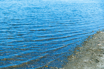 Sea blue water surface with waves near the shore. Background texture.