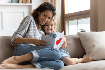 Happy young curly mother reading congratulations in card.