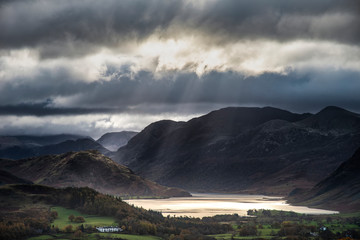 Wall Mural - Majestic sun beams light up Crummock Water in epic Autumn Fall landscape image with Mellbreak and Grasmoor