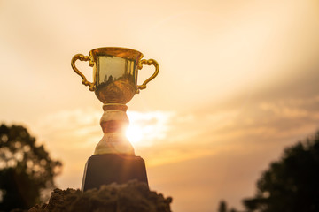 Gold trophy cup on top mountain with sunrise sky.