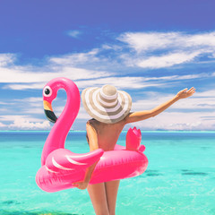 Happy summer vacation fun woman tourist enjoying travel holidays ready for swimming with flamingo float - funny holiday nudist beach concept.